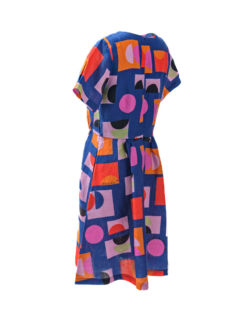 DEVOI Audrina Dress in Just Pretend Blue printed linen. A new version of best selling Dorothy dress. With a blue background and red, orange and pink accents. Side back view.