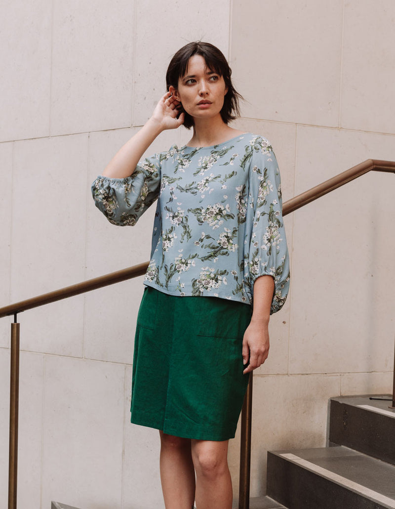 DEVOI Bea top. Blue floral printed long sleeved top with modal crepe. Side front view on model.