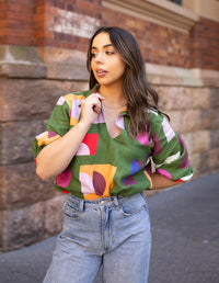 DEVOI Keeva top in Olive Just Pretend print is a loose fitting blouse with a collar and soft v-neck. Wirth half length sleeves, gathered at the cuff. Front view.