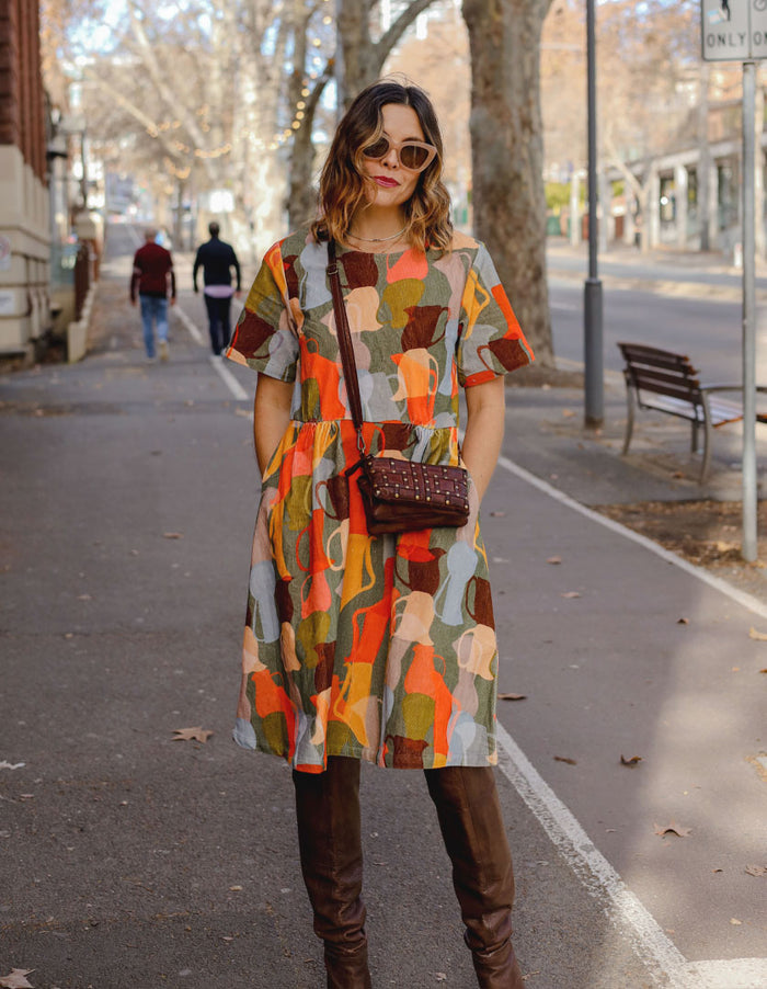 DEVOI Dorothy dress in cotton cord. Printed in Jugs print. Orange and grey colours. Round neckline and gathering at the waist. Front view