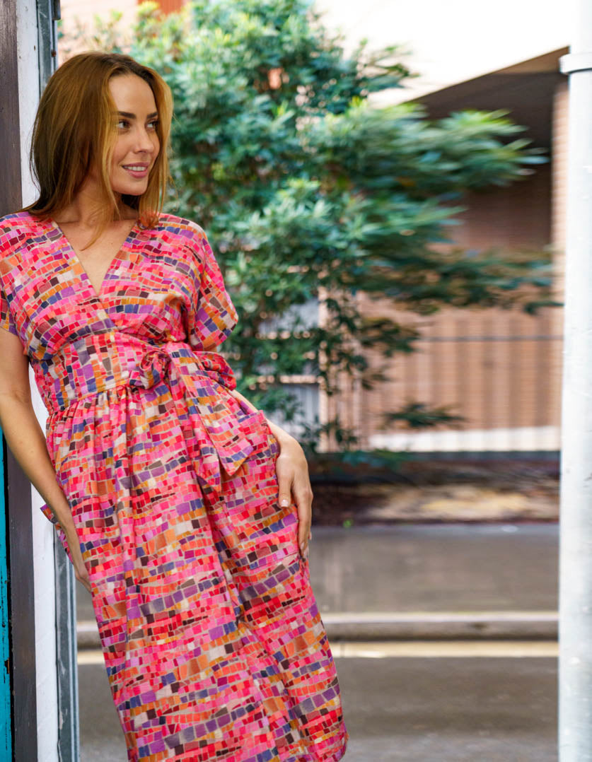 DEVOI Kinsley dress in pink Mosaic printed linen. Wrap dress with a v-neck and short sleeves. Wide waistband. Patch pockets. Front view.