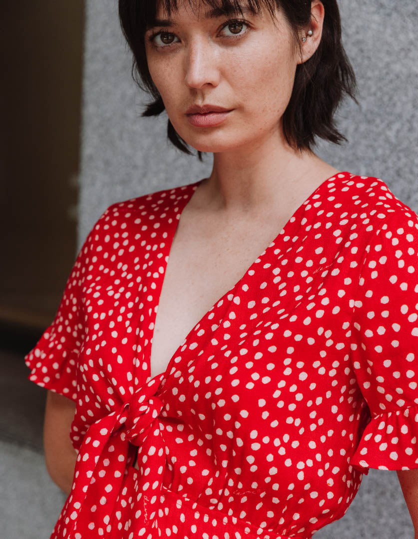 DEVOI dotty red Ellen dress with a v-neck and front tie. Mini dress. Close up on model