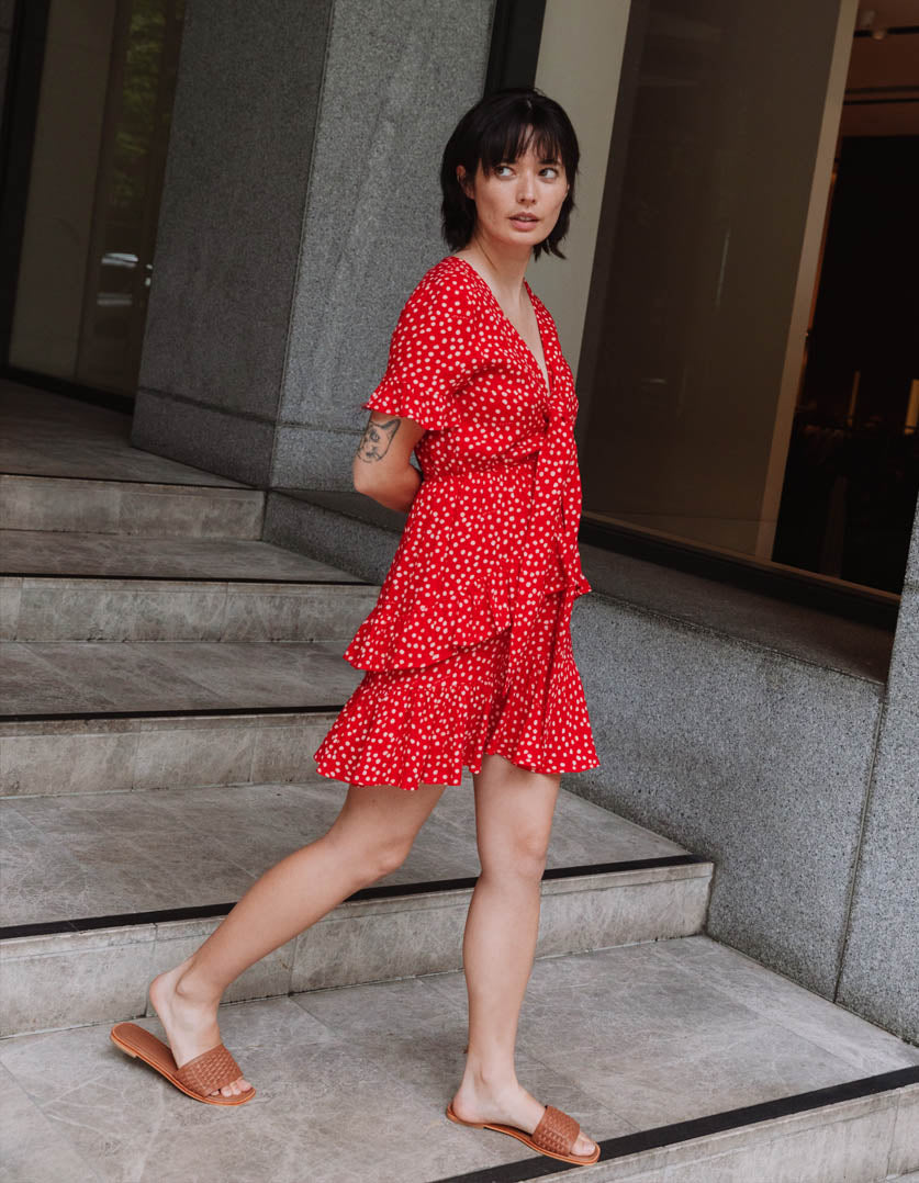 DEVOI dotty red Ellen dress with a v-neck and front tie. Mini dress.Side view on model. Short sleeves.