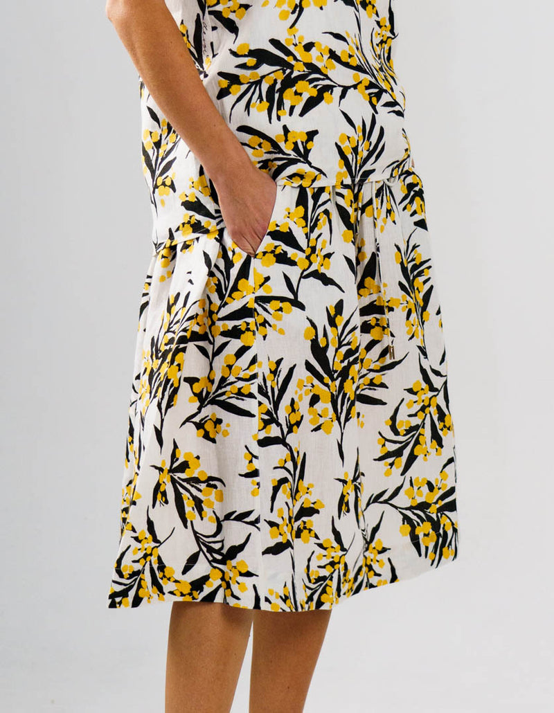 DEVOI Kathleen skirt in golden wattles print. White background with yellow and black. Side view on model